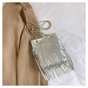 Détail d'un sac à main argenté à franges métalliques avec une bandoulière en chaîne dorée