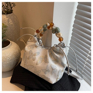 Détail du sac à main en jacquard crème avec poignée perlée et broderie de papillon