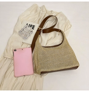 Detail of hand-woven straw hobo bag with brown leather trim on a white dress
