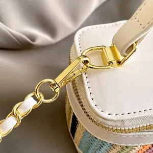 Detail showing the gold metal clasp and chain strap on a woven contrast leather bag