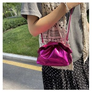 Detail of fuchsia metallic cloud bag with drawstring pleats and slim shoulder strap