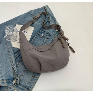 Détail du sac demi-lune en nylon gris foncé avec bandoulière réglable et tirette tissée