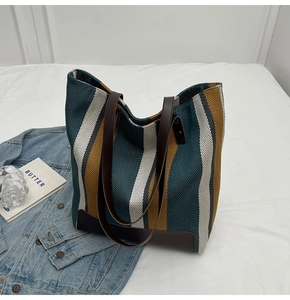 Detail view of the textured woven fabric and brown leather straps on striped tote bag