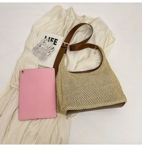 Detail of woven straw handbag with brown leather strap on cream pleated dress