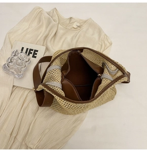 Close-up of woven straw tote bag with brown leather strap and inner zipper pouch
