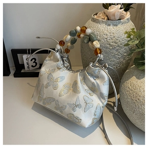 Détail de la broderie papillon de haute qualité et de la poignée perlée sur un sac à main