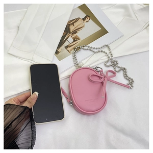 Detalle del mini bolso bandolera rosa ovalado con lazo decorativo y cadena de bolas de plata
