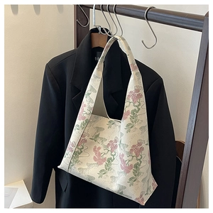 Detailed view of vintage floral embroidery on an elegant off-white underarm bucket bag