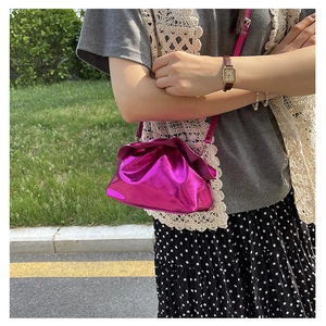 Detail of fuchsia metallic crossbody bag with gathered closure and slim leather shoulder strap