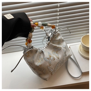 Détail de la broderie papillon et poignée perlée sur sac à main en soie chinois