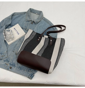 Close-up of a striped canvas tote bag with brown leather straps and textured fabric detail