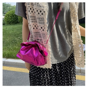 Outdoor shot of metallic pink drawstring crossbody bag with textured pleated leather finish