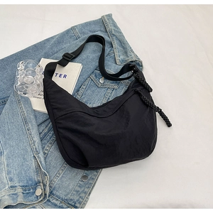 Sac bandoulière en nylon noir avec sangle réglable et détail de fermeture tressée