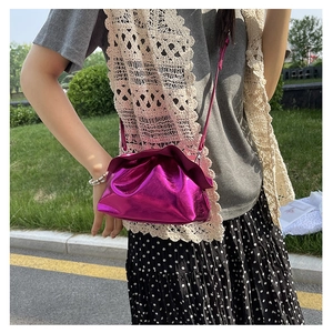 Close-up of bright purple metallic ruched crossbody bag with drawstring design