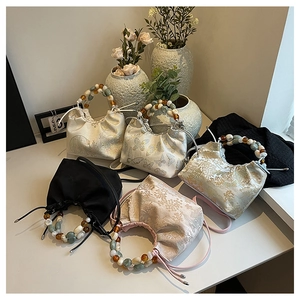 Détail de sacs seaux de style chinois avec broderies florales et poignées en perles