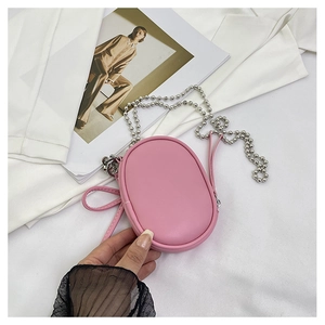 Mini bolso ovalado rosa con cadena de bolas metálicas y cremallera en una modelo