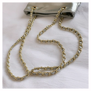 Détail du sac bandoulière argenté en similicuir avec chaînes métalliques dorées et argent