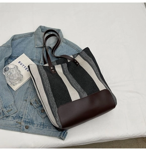 Detailed close-up of striped canvas tote bag fabric with premium brown leather handle