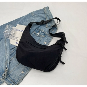 Détail du sac croissant en nylon noir avec bandoulière réglable et tirette tressée