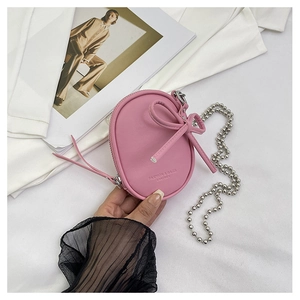 Detalle de mini bolso de cuero rosa con lazo decorativo y cadena de bolas plateada