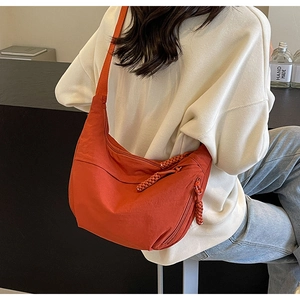 Détail d'un grand sac bandoulière orange en nylon avec fermeture éclair et languette