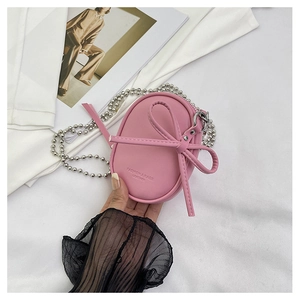 Detalle de mini bolso rosa con adorno de lazo y correa de cadena de metal plata