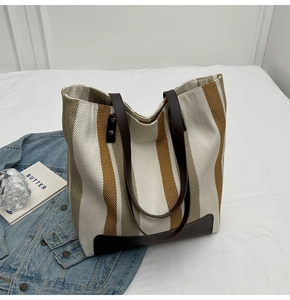 Detail of canvas tote bag with brown and white stripes and leather corner reinforcement