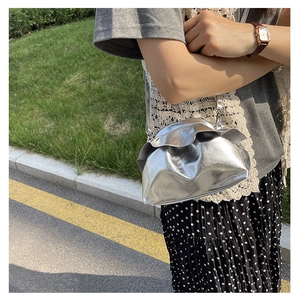 Detail of silver metallic cloud bag with gathered pleats and shiny mirror finish