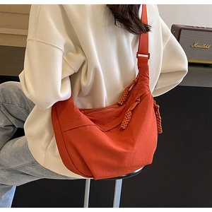 Détail du sac bandoulière croissant en nylon orange avec sangle réglable et tirette tissée