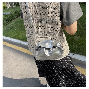 Detail of silver metallic cloud bag featuring ruched texture and slim chain strap