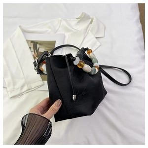 Détail du sac seau en jacquard noir avec poignée perlée colorée et motif floral en satin