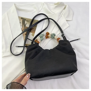 Détail d'un sac à main en satin noir avec motifs floraux et poignée en perles colorées