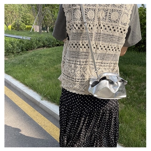 Detailed side view of a metallic silver ruched cloud crossbody bag with thin leather strap