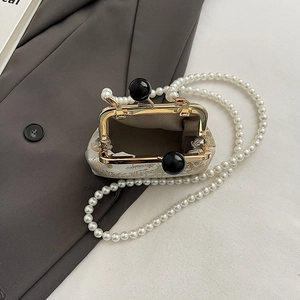 Close-up of vintage brocade handbag featuring gold kiss-lock and pearl shoulder strap