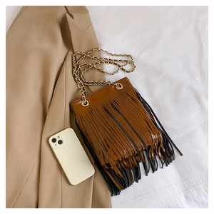Détail d'un sac bandoulière en cuir marron avec des franges noires et une chaîne dorée chic