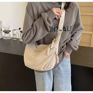 Détail du sac croissant en nylon beige avec fermeture éclair tressée et large bandoulière