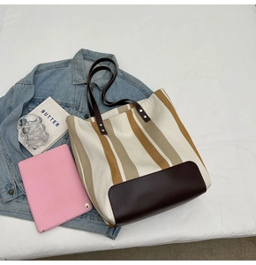 Detailed top view of striped canvas tote bag with brown leather base and daily essentials