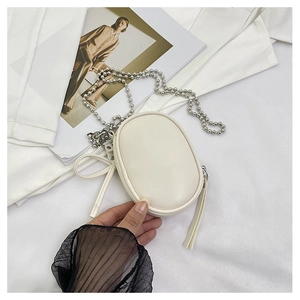 Detalle de mini bolso blanco con cadena, cremallera de borla larga y adorno de lazo