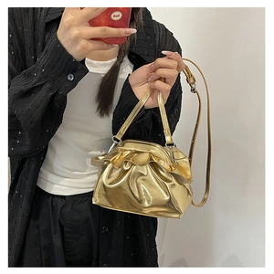 Detail view of gold metallic pleated handbag with vintage clasp and slim shoulder strap