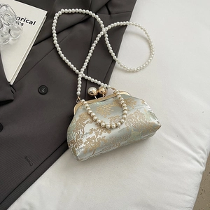 Detail of vintage embroidered clutch with pearl straps on a grey suit jacket