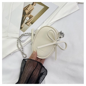 Detalle del mini bolso bandolera blanco crema con un lazo grande y cadena plateada