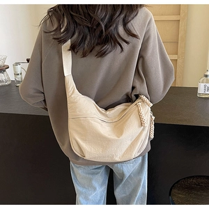 Détail du sac croissant en nylon crème avec large bandoulière et tirette de zip tissée