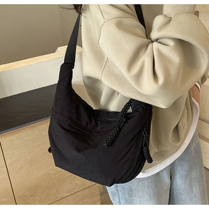 Détail d'un grand sac croissant en nylon noir avec fermeture à corde et bandoulière