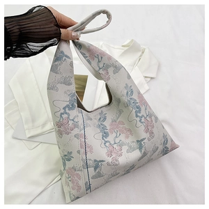 Close-up of crane and floral embroidery on a jacquard bucket bag with top handle