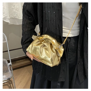 Detail of metallic gold pleated cloud bag with shiny texture and slender shoulder strap