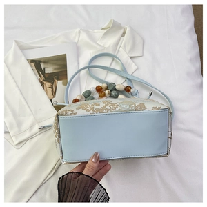 Détail du sac boîte bleu clair avec paysages chinois et poignée en perles colorées