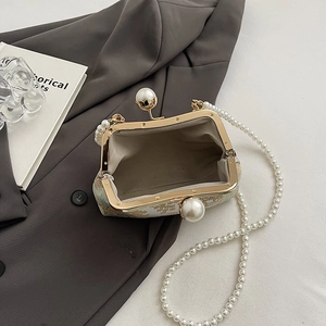 Detail of vintage embroidered floral clutch with gold metal frame and pearl clasp