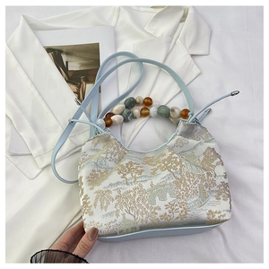Détail du sac bleu clair style chinois avec broderie paysage et poignée perles