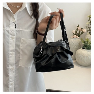Detail of black glossy pleated handbag featuring elegant ruffled texture and silver hooks