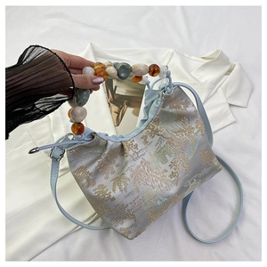 Détail du sac brodé oriental bleu clair avec poignée en perles de résine et cordon de serrage